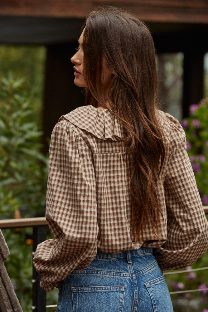 Woman wearing a checkered shirt and blue jeans with a blurred background
