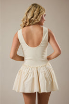 Woman wearing a cream-colored dress with a plain background