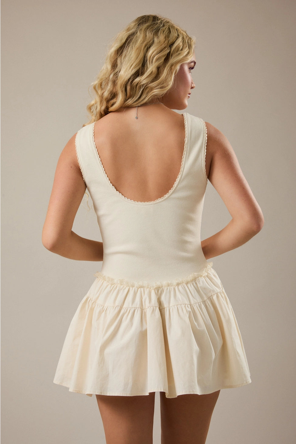 Woman wearing a cream-colored dress with a plain background